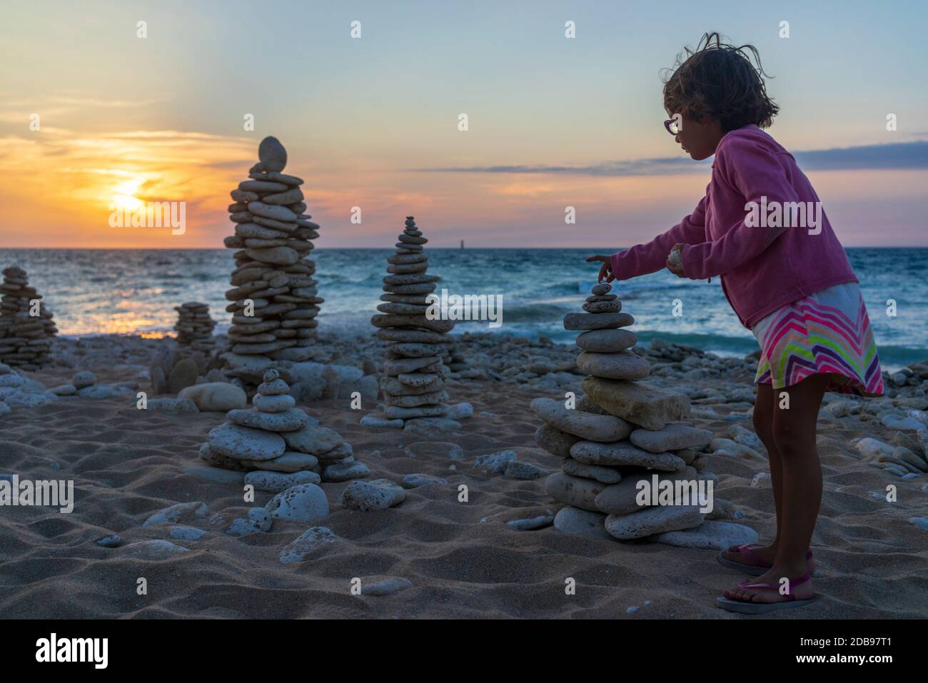 Girl stacking pebbles on beach Stock Photo Alamy