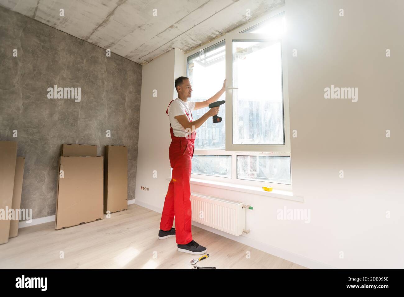 master with a screwdriver sets fittings on the window Stock Photo