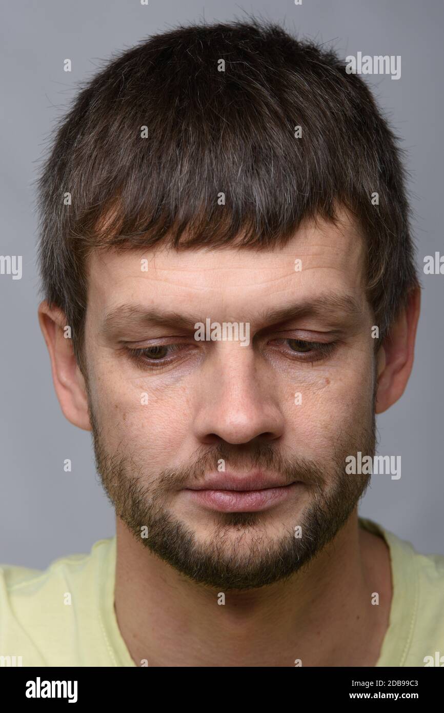 Close-up portrait of a grieved downcast European-looking man who puffed out his cheeks Stock Photo