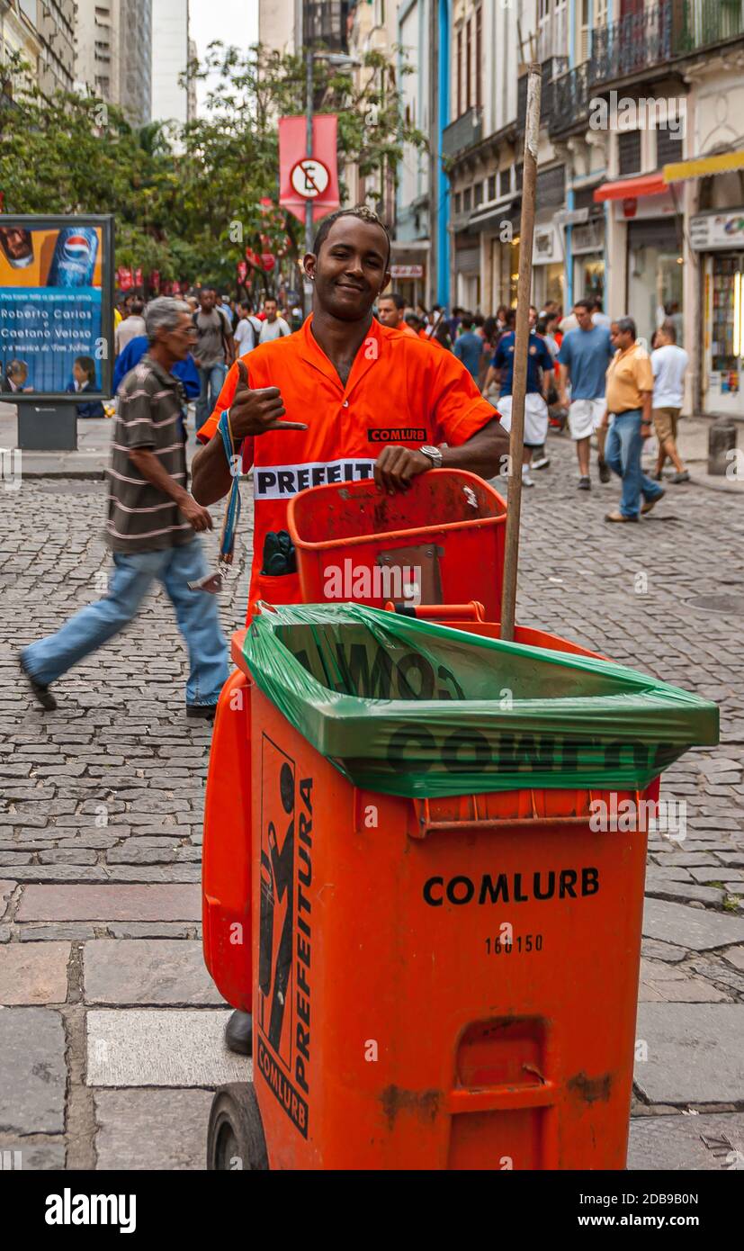 Rio de Janeiro, Brazil - December 26, 2008: El Centro district. Colored city garbage collector in orange garb shows the Shaka sign with his right hand Stock Photo
