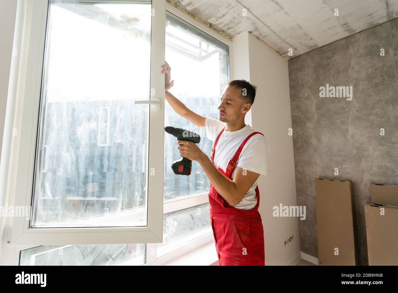 master with a screwdriver sets fittings on the window Stock Photo
