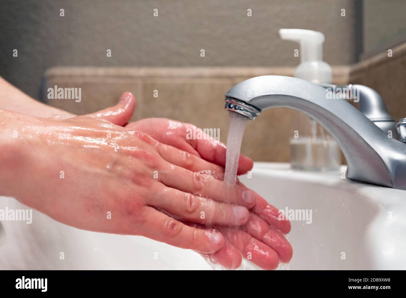 Washing hands with water in bathroom sink, hygiene to stay healthy Stock Photo