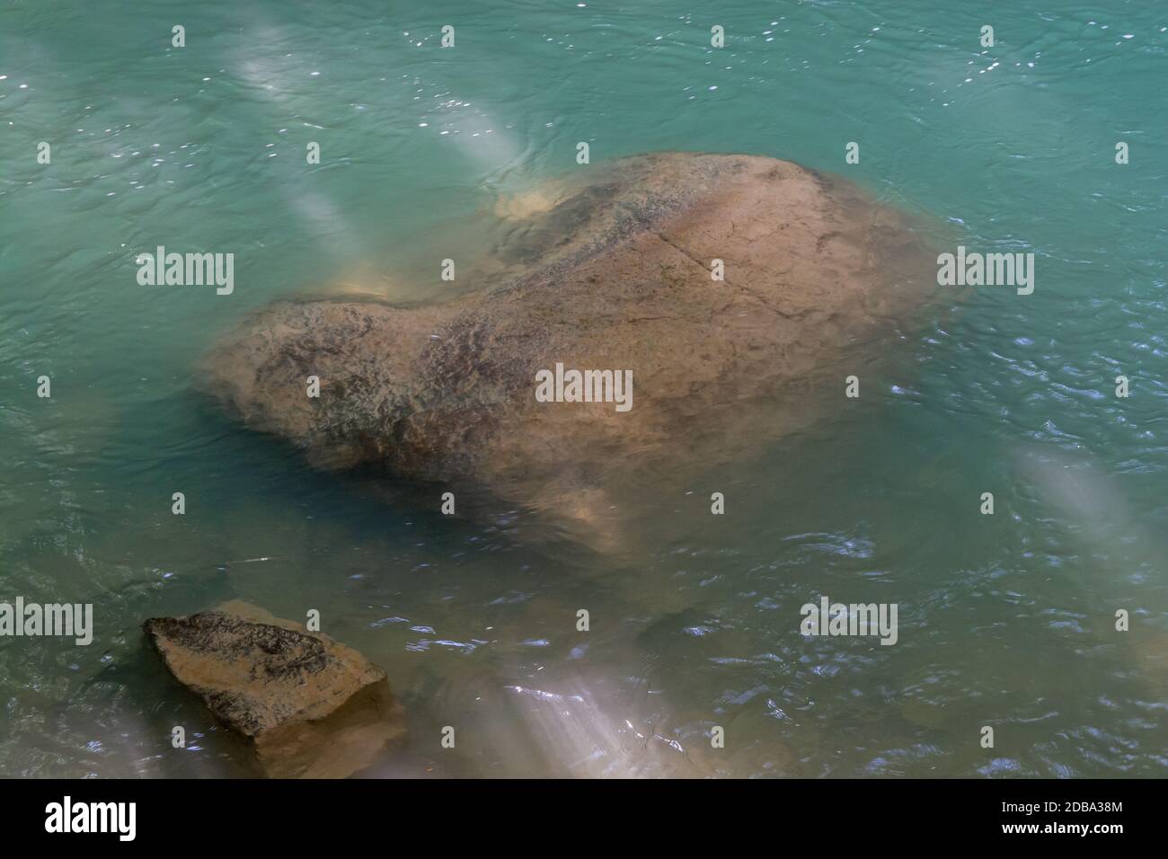 Big Boulder protruding out of crystal clear river water Stock Photo