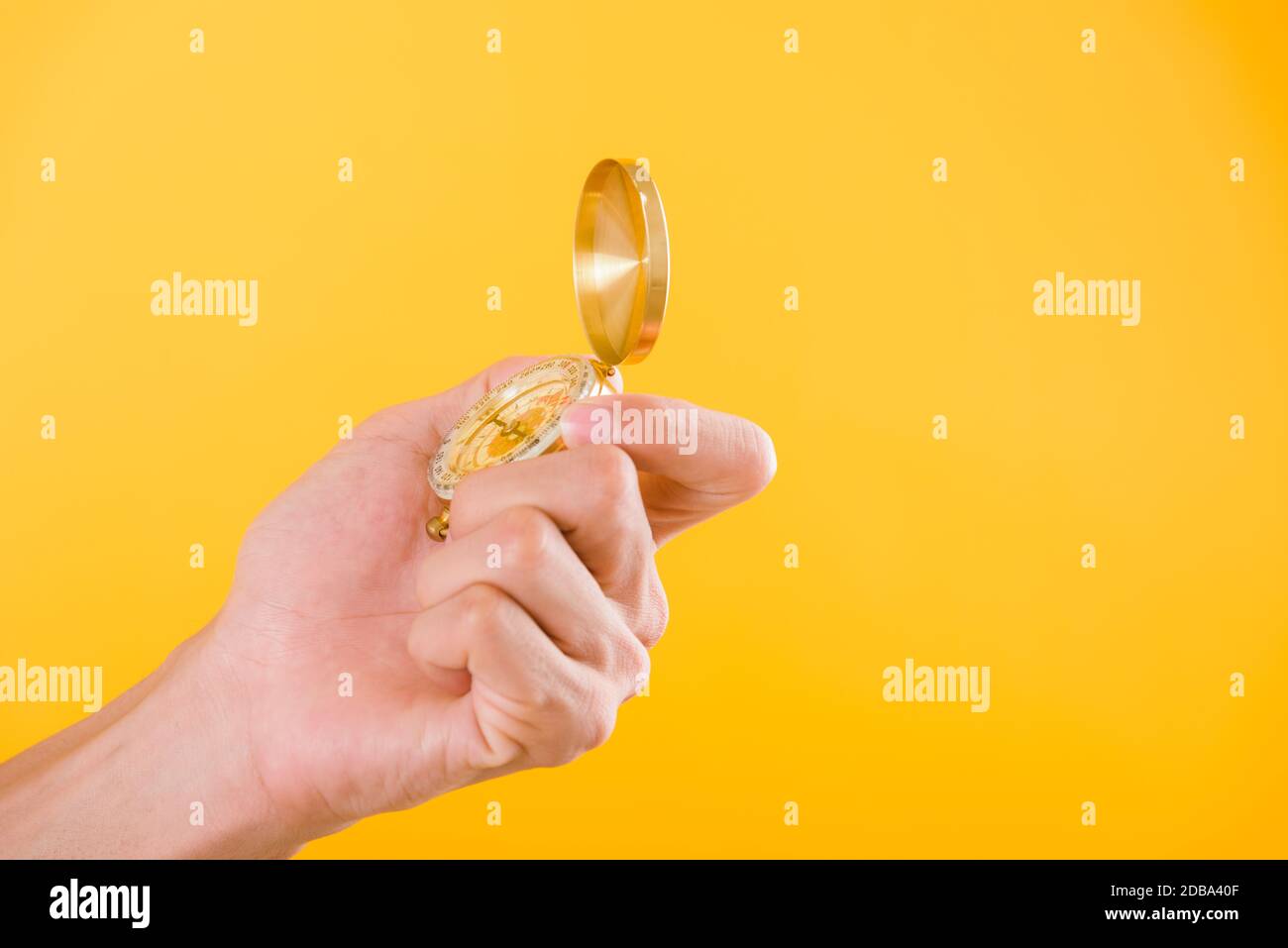Hand holding antique brass compass isolated on yellow background with copy space for text Stock Photo