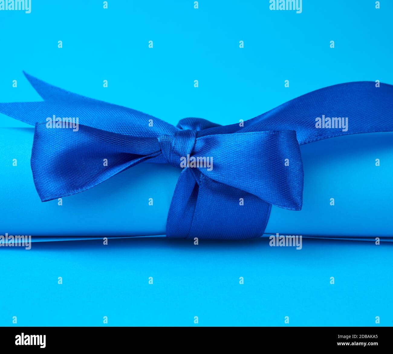 roll of blue paper tied with a silk blue ribbon, blue background, close ...