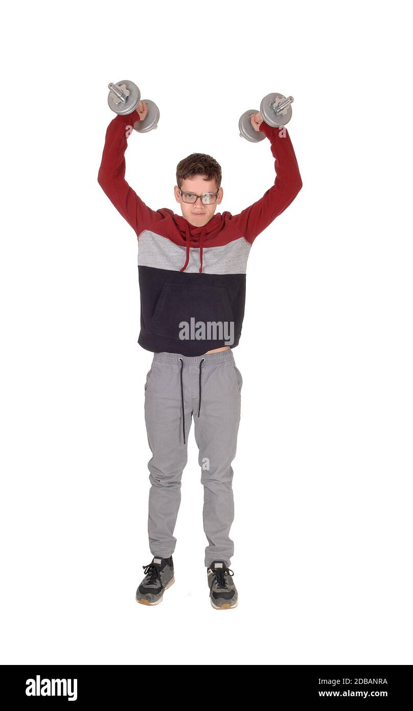 A handsome young teenager standing in the studio exercising with his  two dumbbells, full lengths, isolated for white background Stock Photo