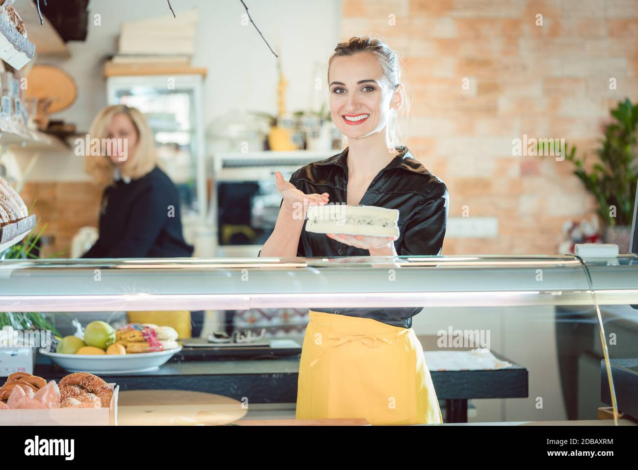Friendly women selling cheese at counter in a supermarket Stock Photo