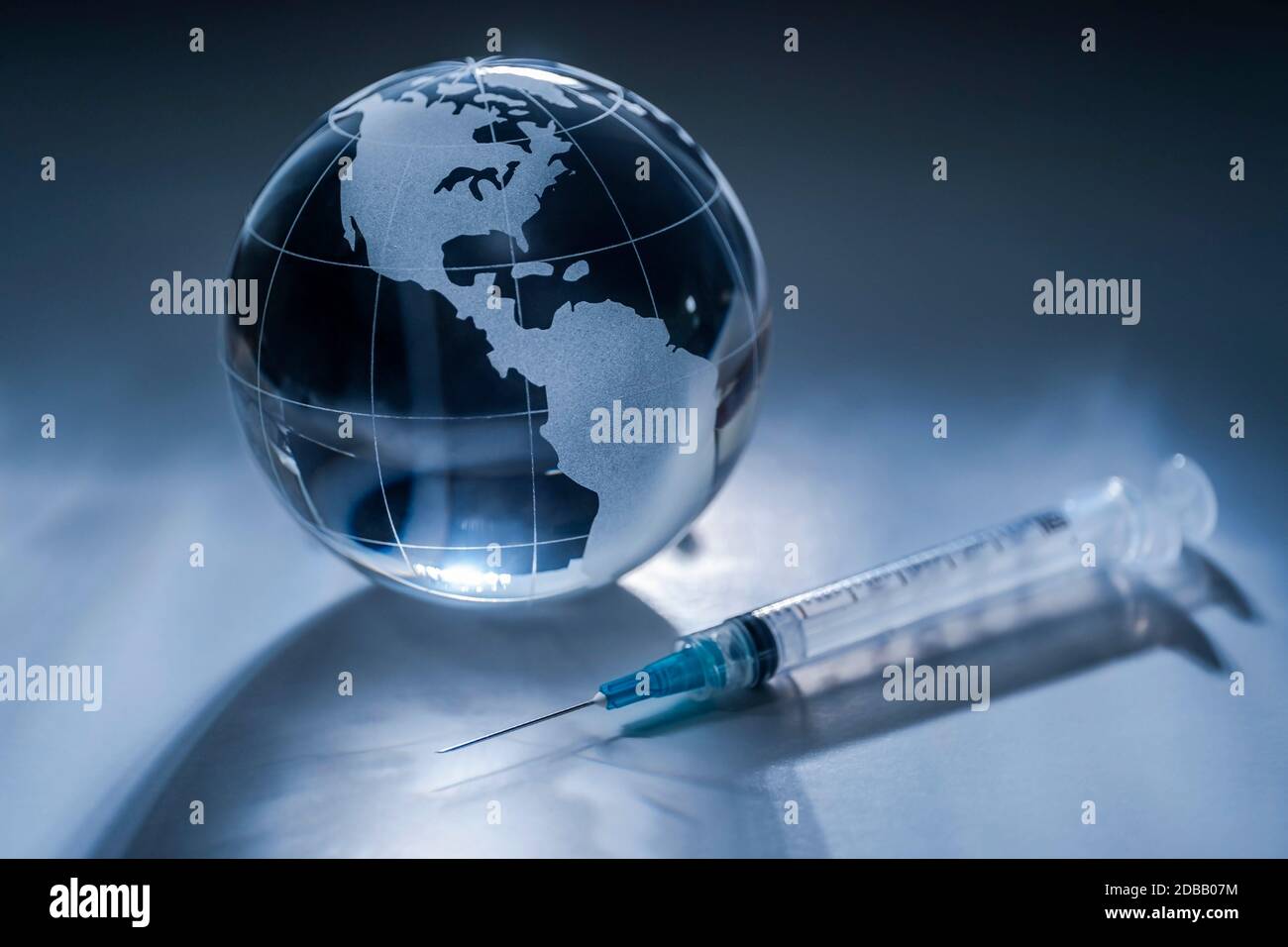 Glass globe and syringe on gray background Stock Photo