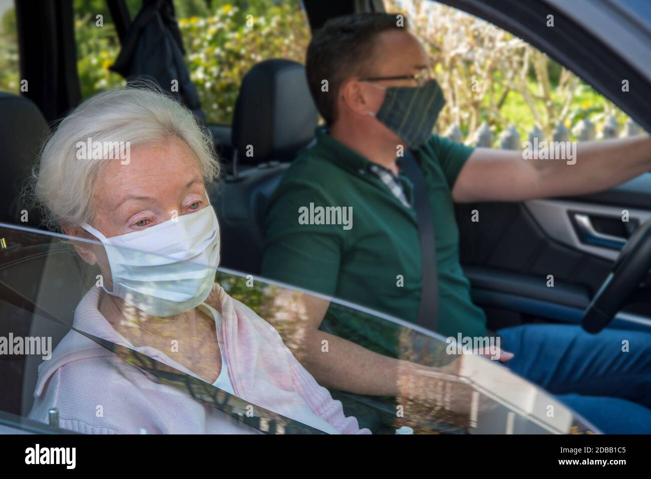 Senior woman and son with face masks driving in the car Stock Photo