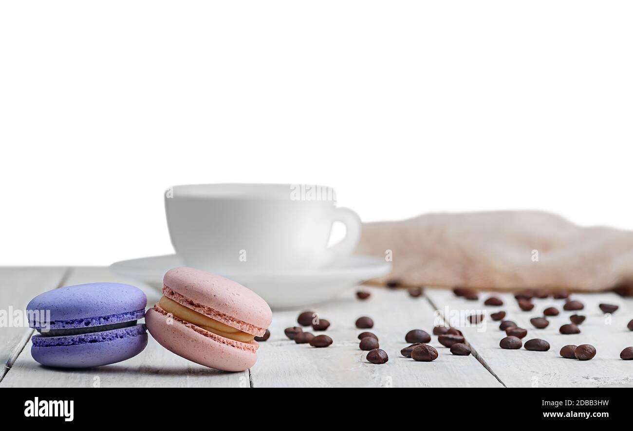 Two macaroons with a cup, coffee beans and towel isolated on white ...