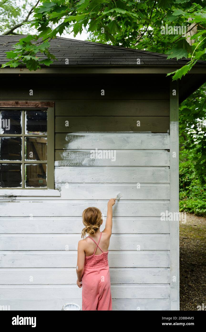 Girl (6-7) painting cottage wall Stock Photo