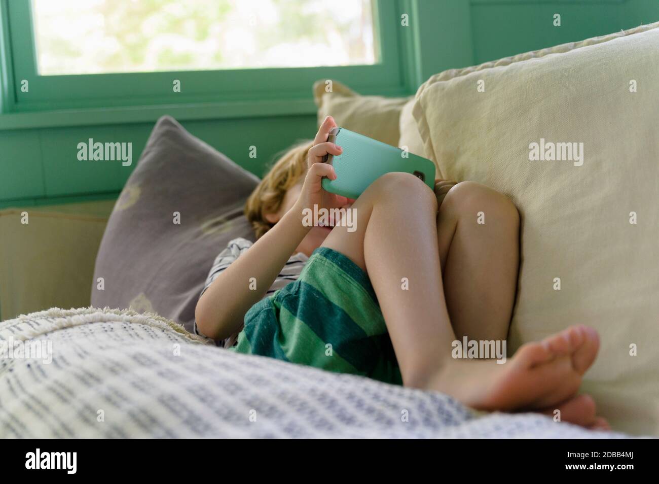 Boy (4-5) using smartphone on sofa Stock Photo