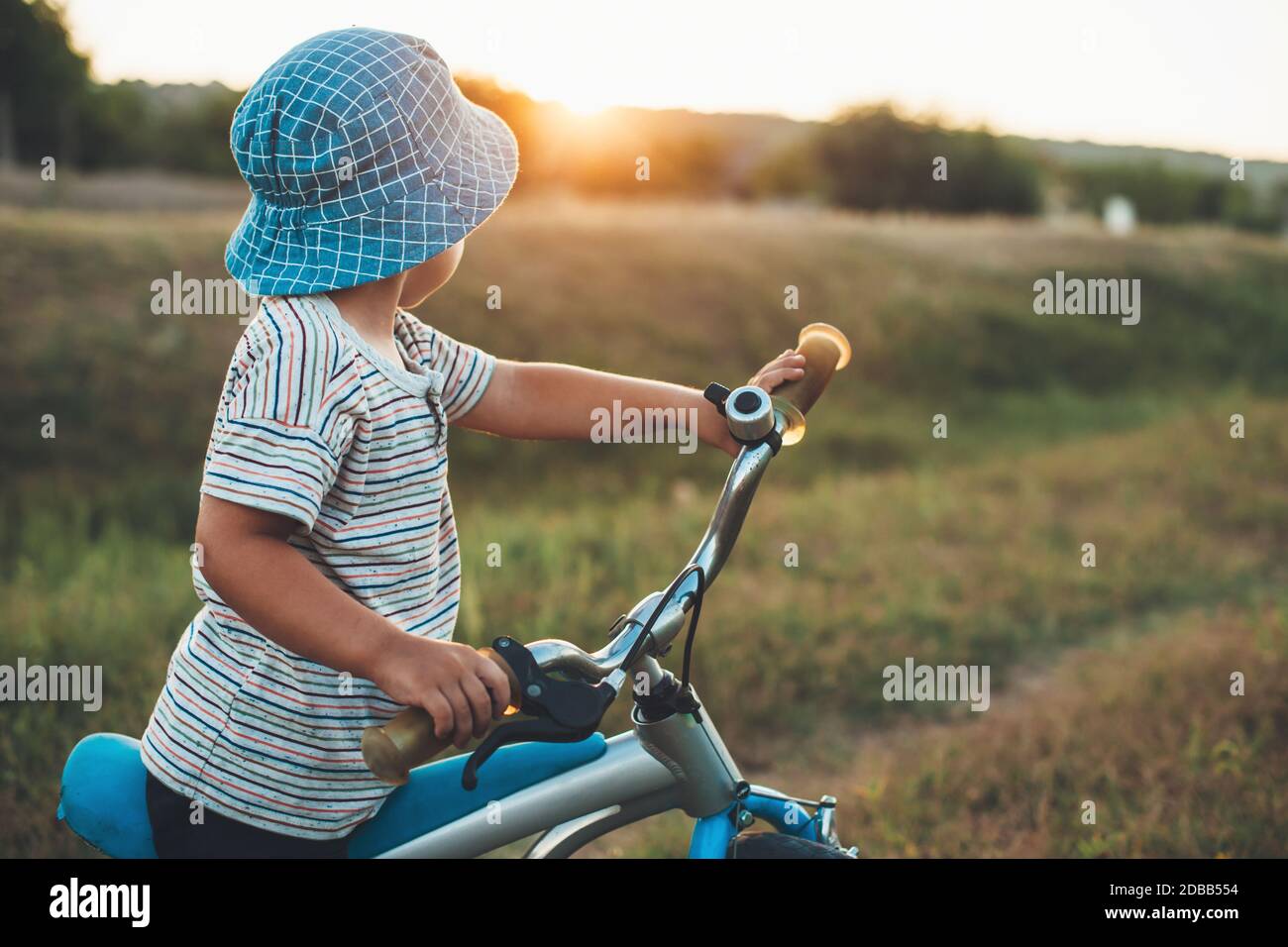 Side view photo of a caucasian boy with a hat riding a bike in the ...