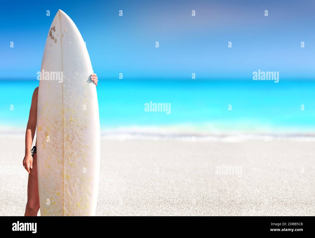 Girl holding a surfboard in a white sand tropical beach Stock Photo