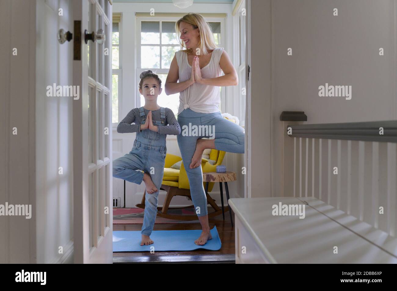 Mother with daughter (6-7) practicing yoga together at home Stock Photo