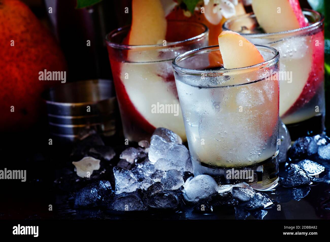 Alcoholic cocktail with pear, vodka, sprite, crushed ice and lime juice, black background