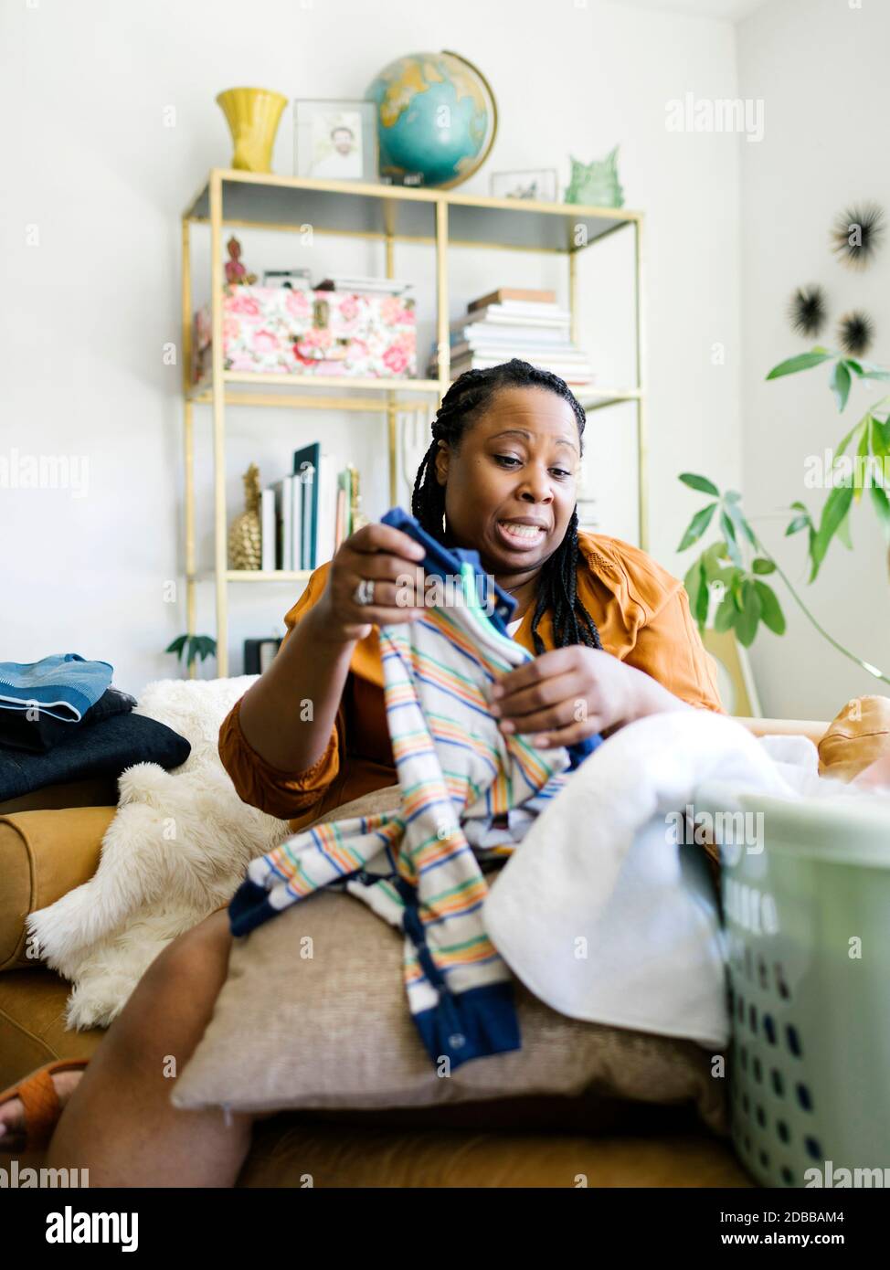 Woman folding baby clothing at home Stock Photo
