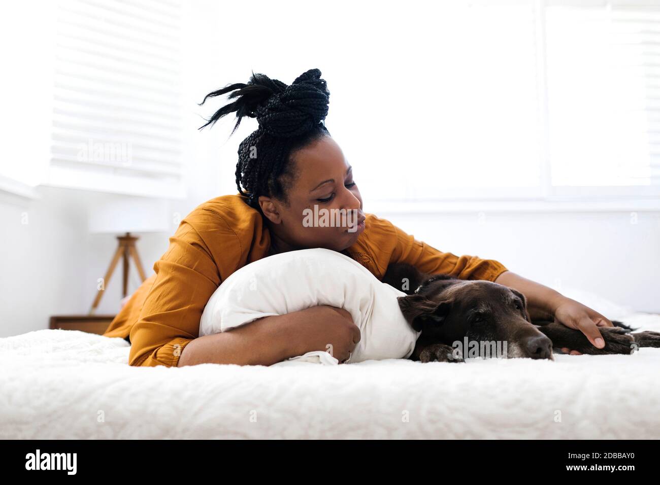 Woman lying on bed with dog Stock Photo