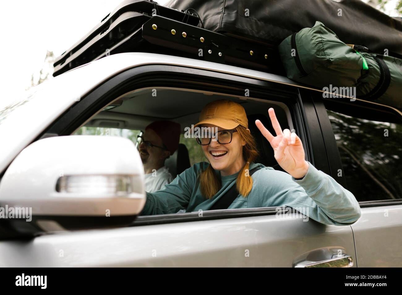 Woman and man sitting in off road car with tent on roof Stock Photo