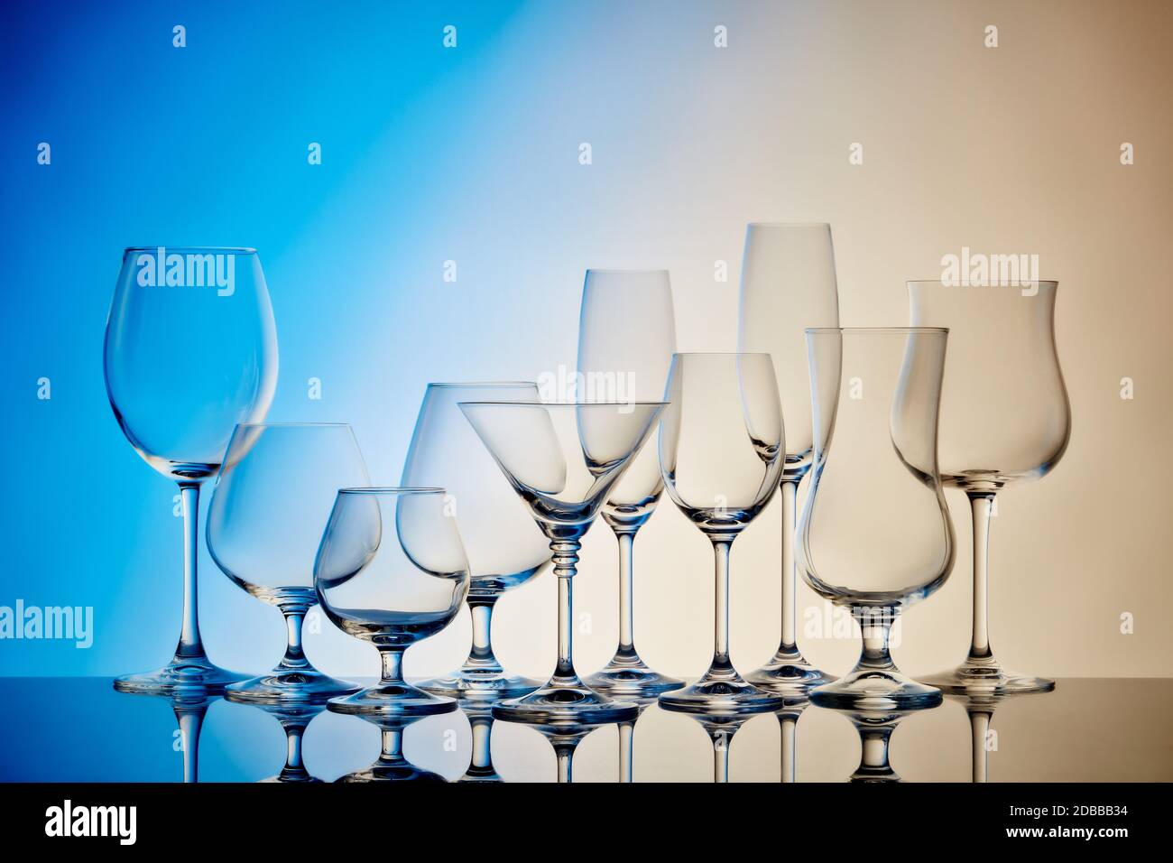Set of glasses for different alcoholic drinks and cocktails on light