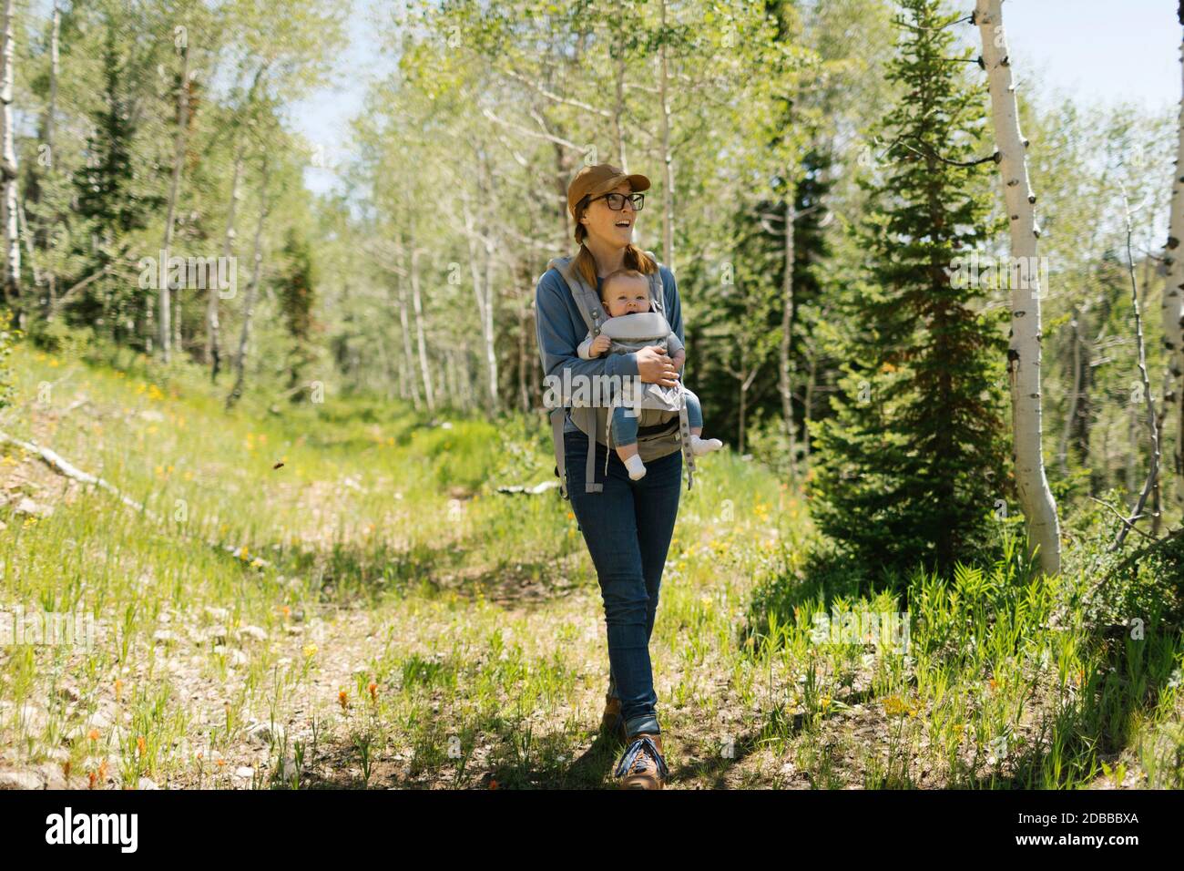 USA, Utah, Uinta National Park, Smiling woman with baby son (6-11 months) in baby carrier in forest Stock Photo