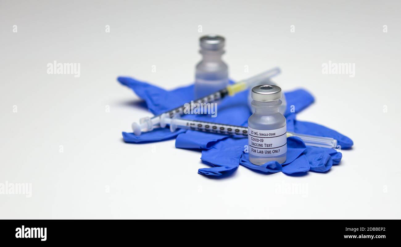 A pair of Covid-19 test vaccine vials on top of blue rubber medical ...