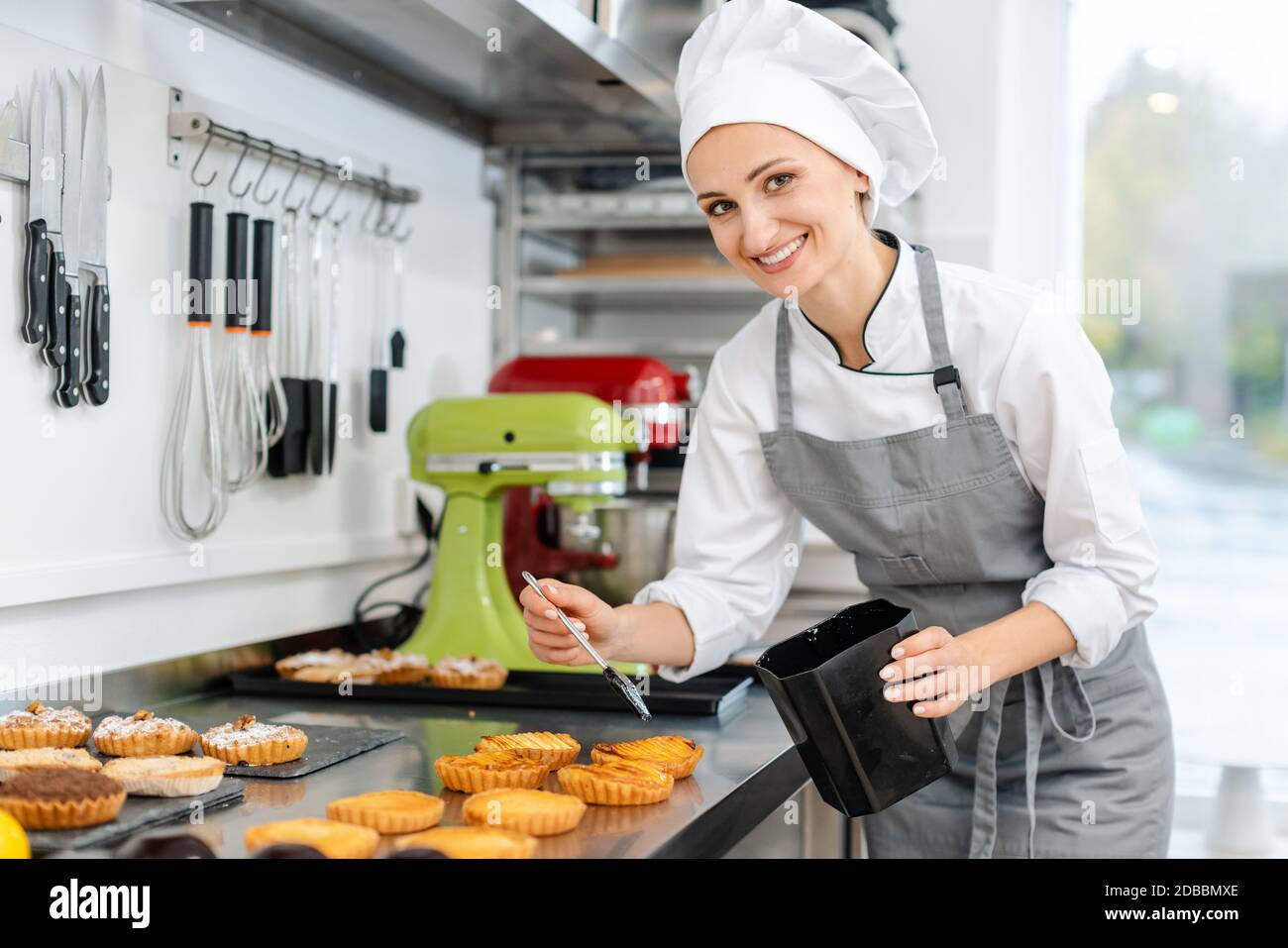 Pastry chef woman glazing little cakes Stock Photo