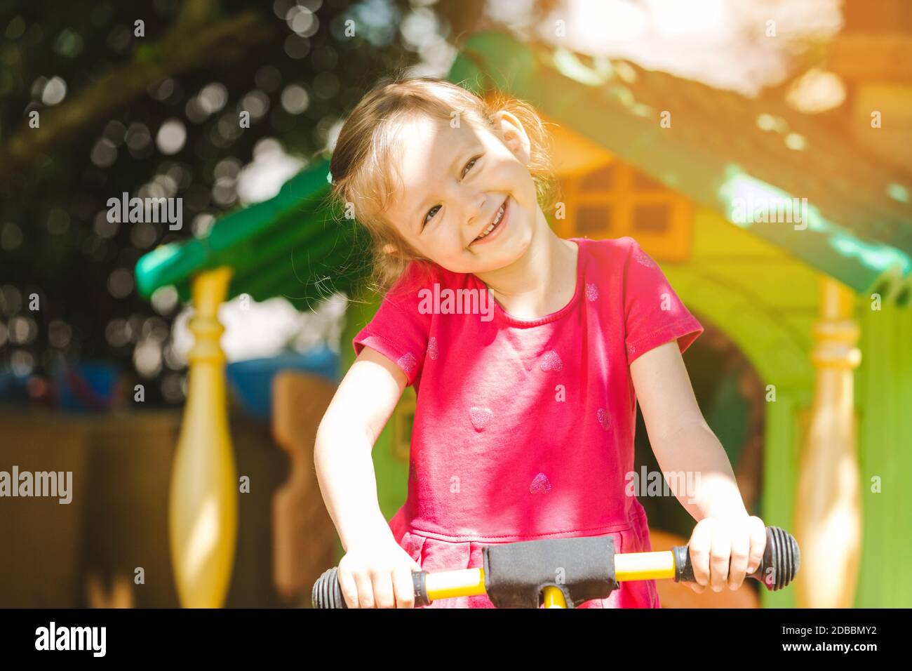 Girl child playing outdoors in the sun smiling into the camera Stock ...