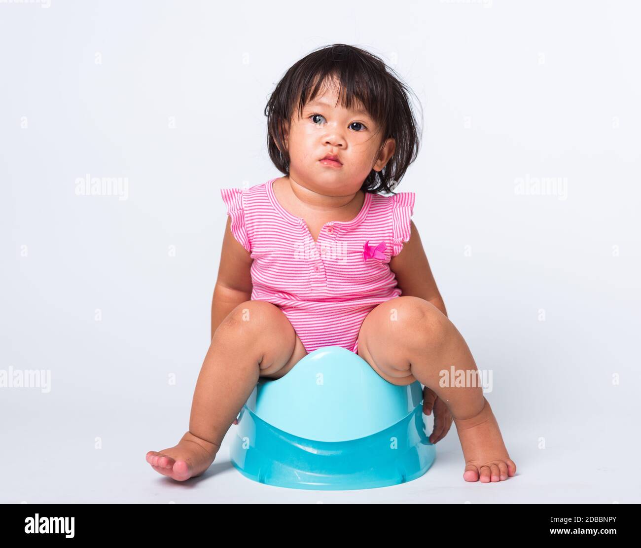 Asian little cute baby child girl education training to sitting on blue chamber pot or potty in, studio shot isolated on white background, wc toilet c Stock Photo