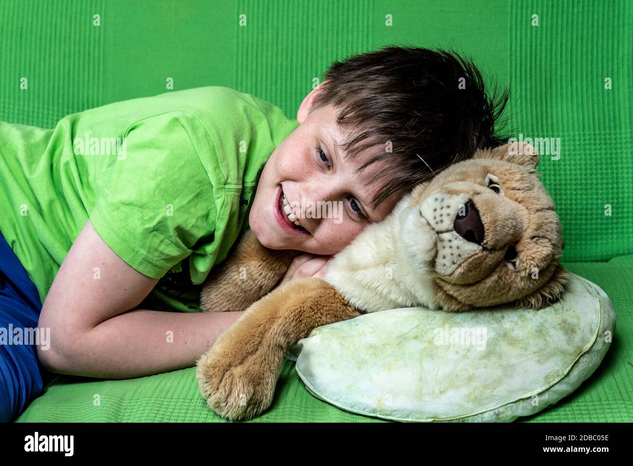 Smiling boy with a plush toy laying on a couch Stock Photo