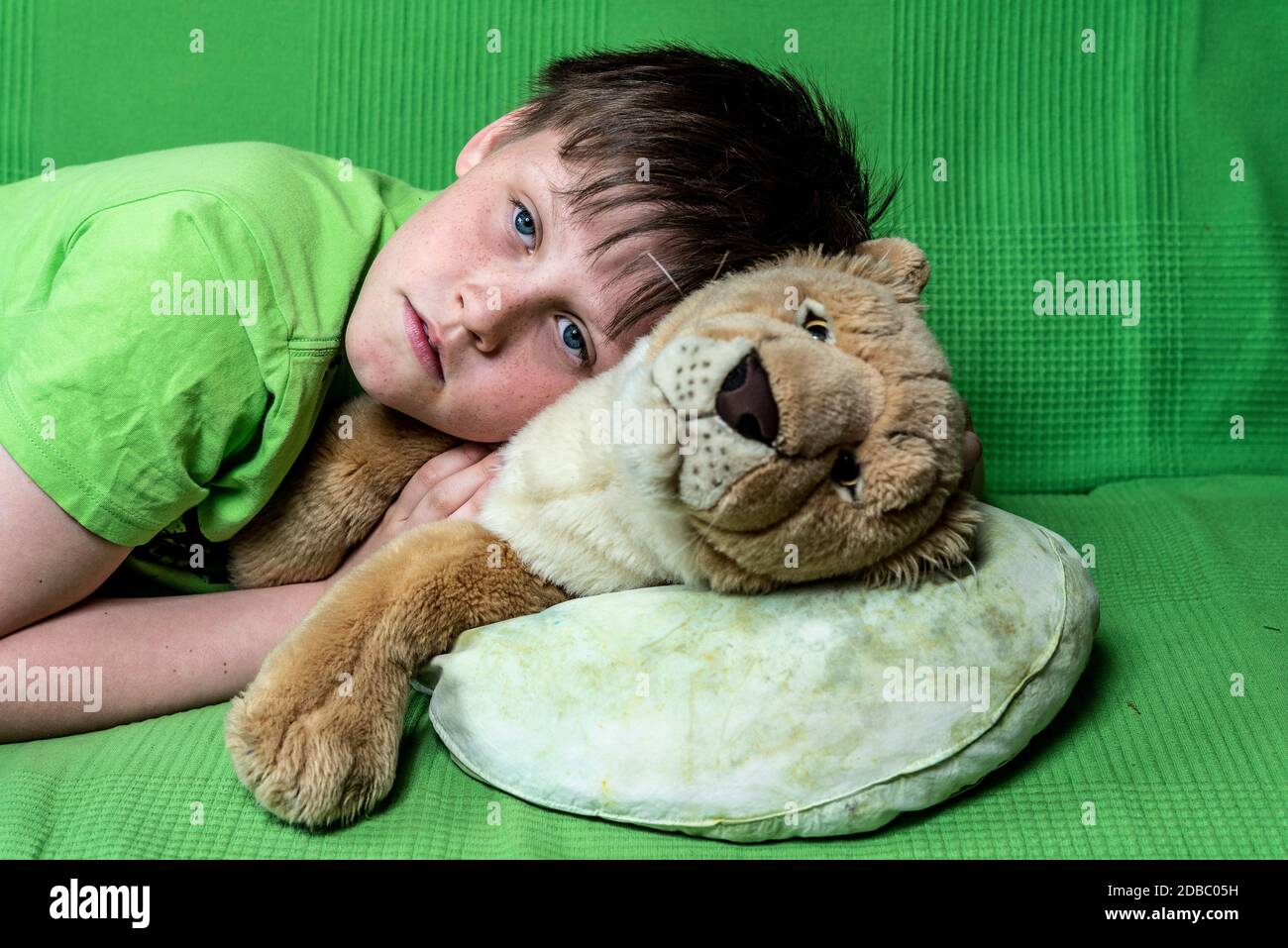 Boy with a plush toy laying on a sofa Stock Photo