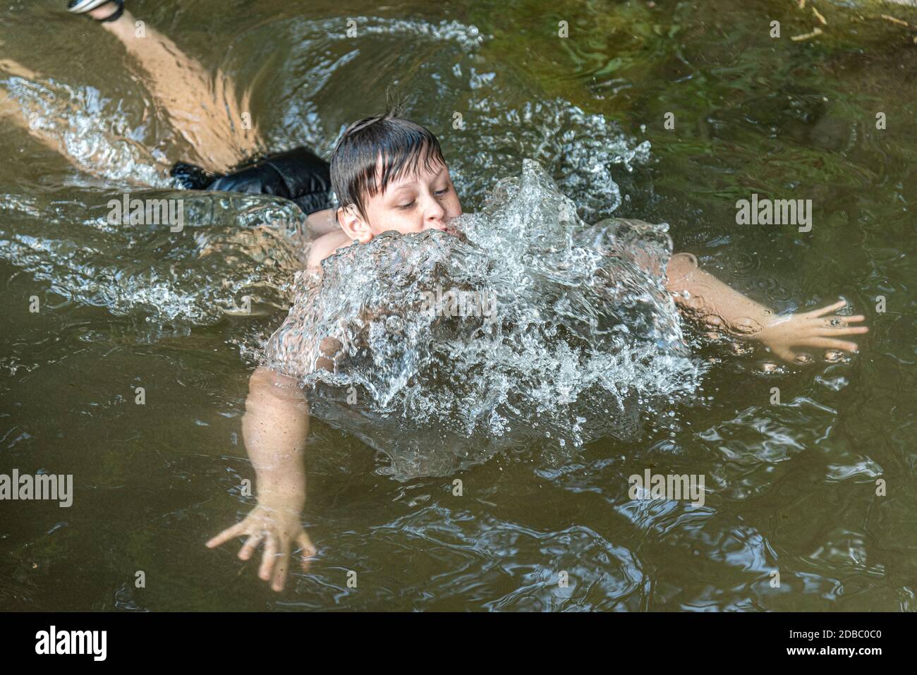 Boy swimming in a pond, water splashes Stock Photo