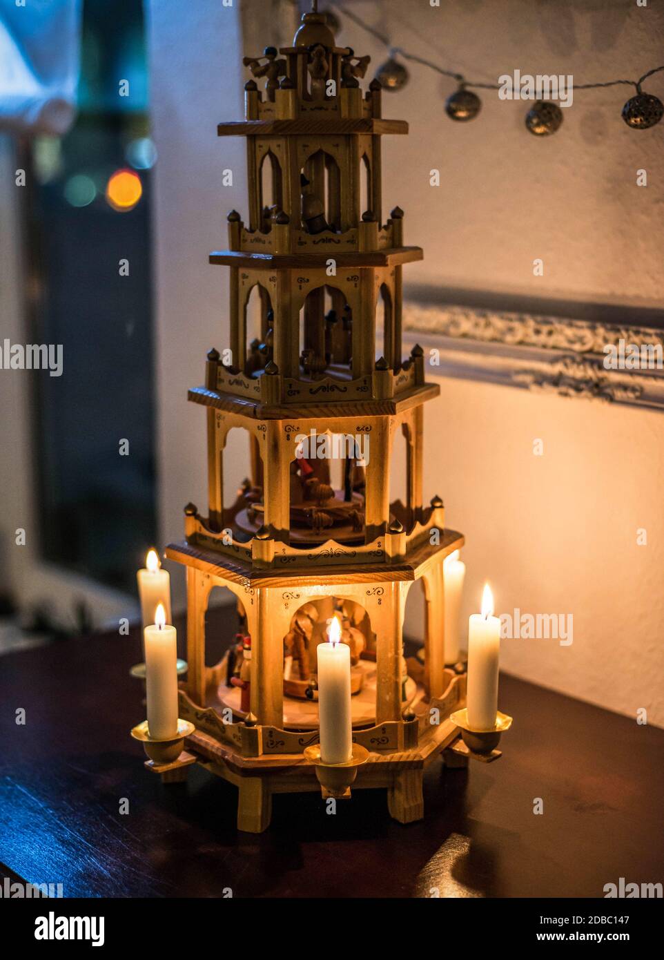 Traditional Christmas decoration. Candles burning on a wooden Christmas carousel with nativity scene and wood sculptural Christmas characters. Stock Photo