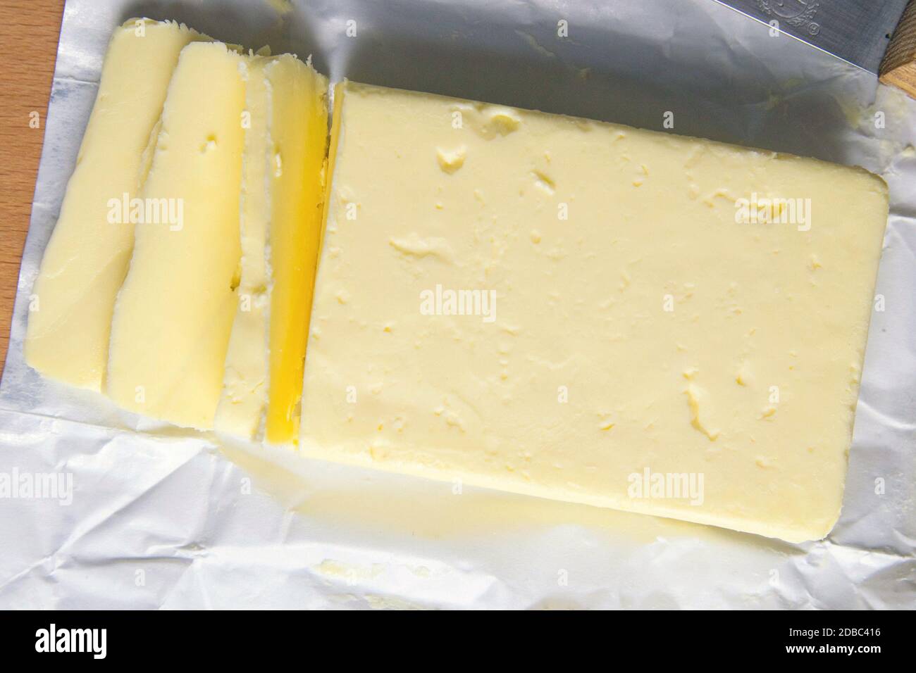 Piece of unwrapped butter on wooden table. Top views, close-up. Stock Photo
