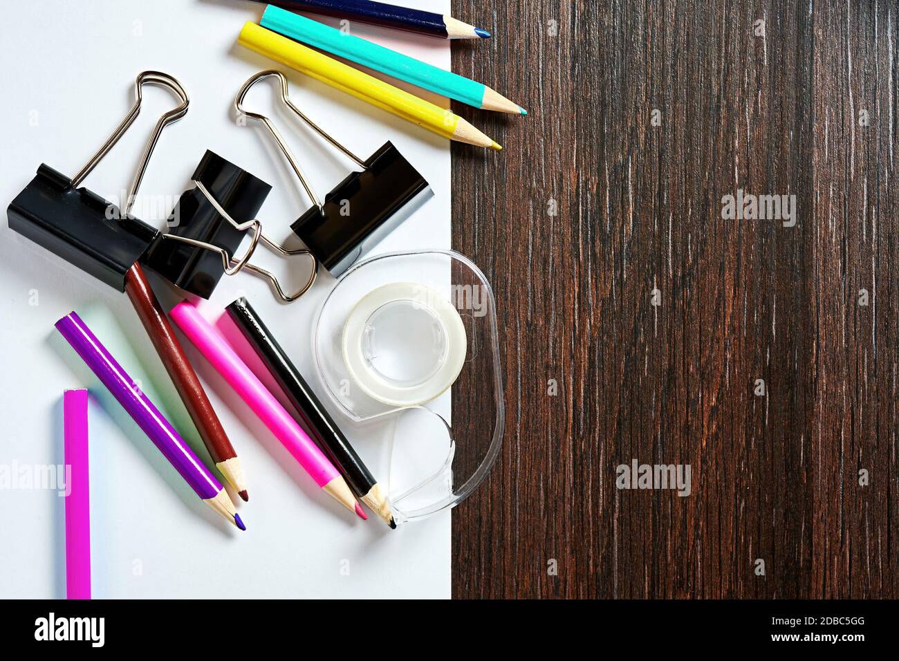 Set of colored pencils, paper clips on the wooden table with white ...