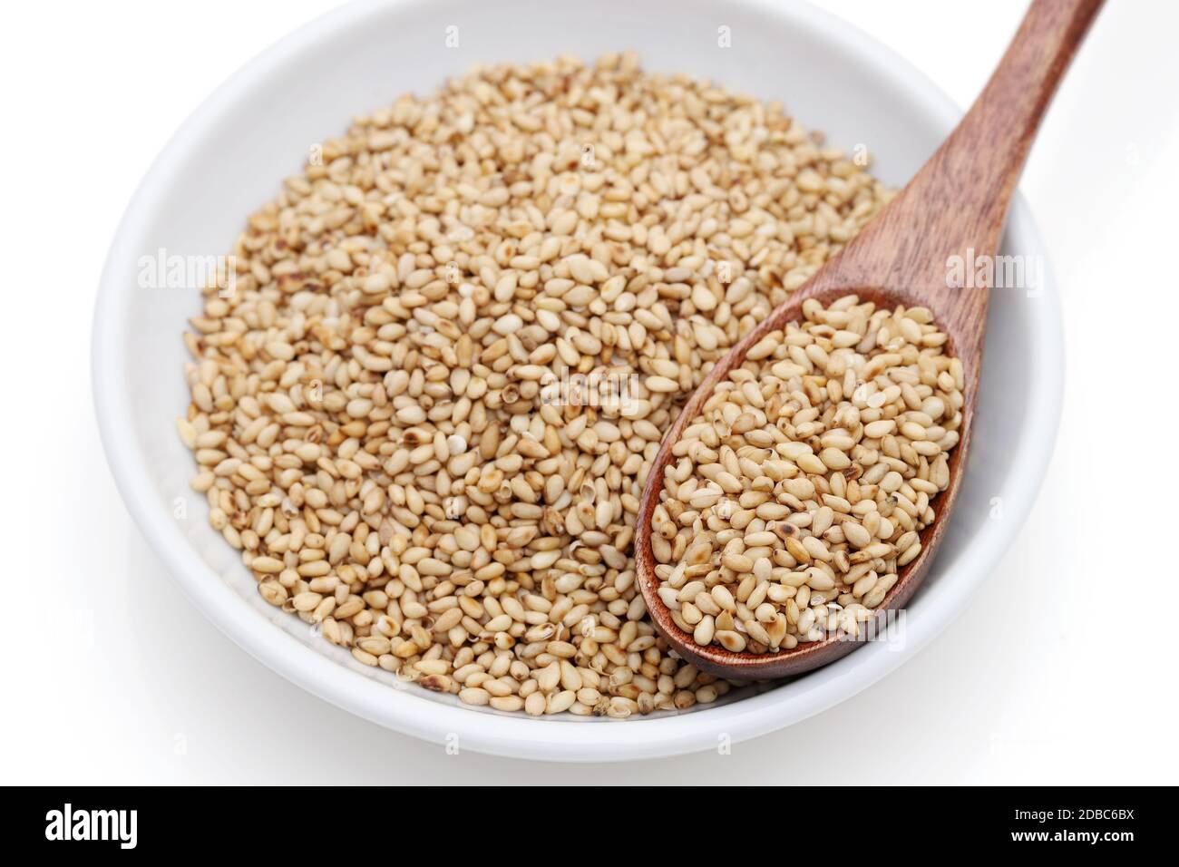 White sesame seeds with wooden spoon in a dish on white background Stock Photo