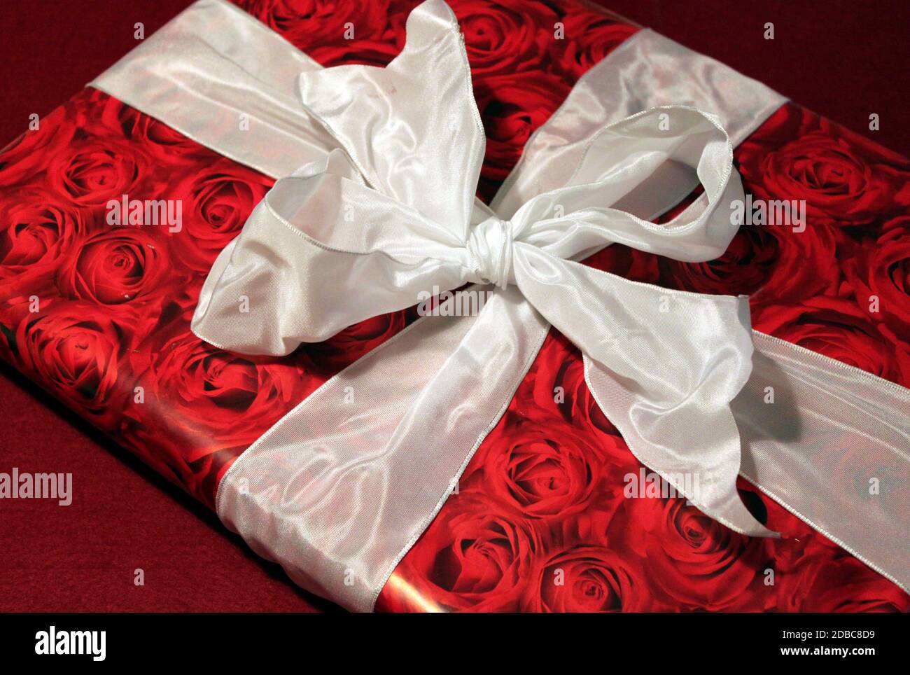 Gift with red roses wrapping paper and white bow Stock Photo - Alamy