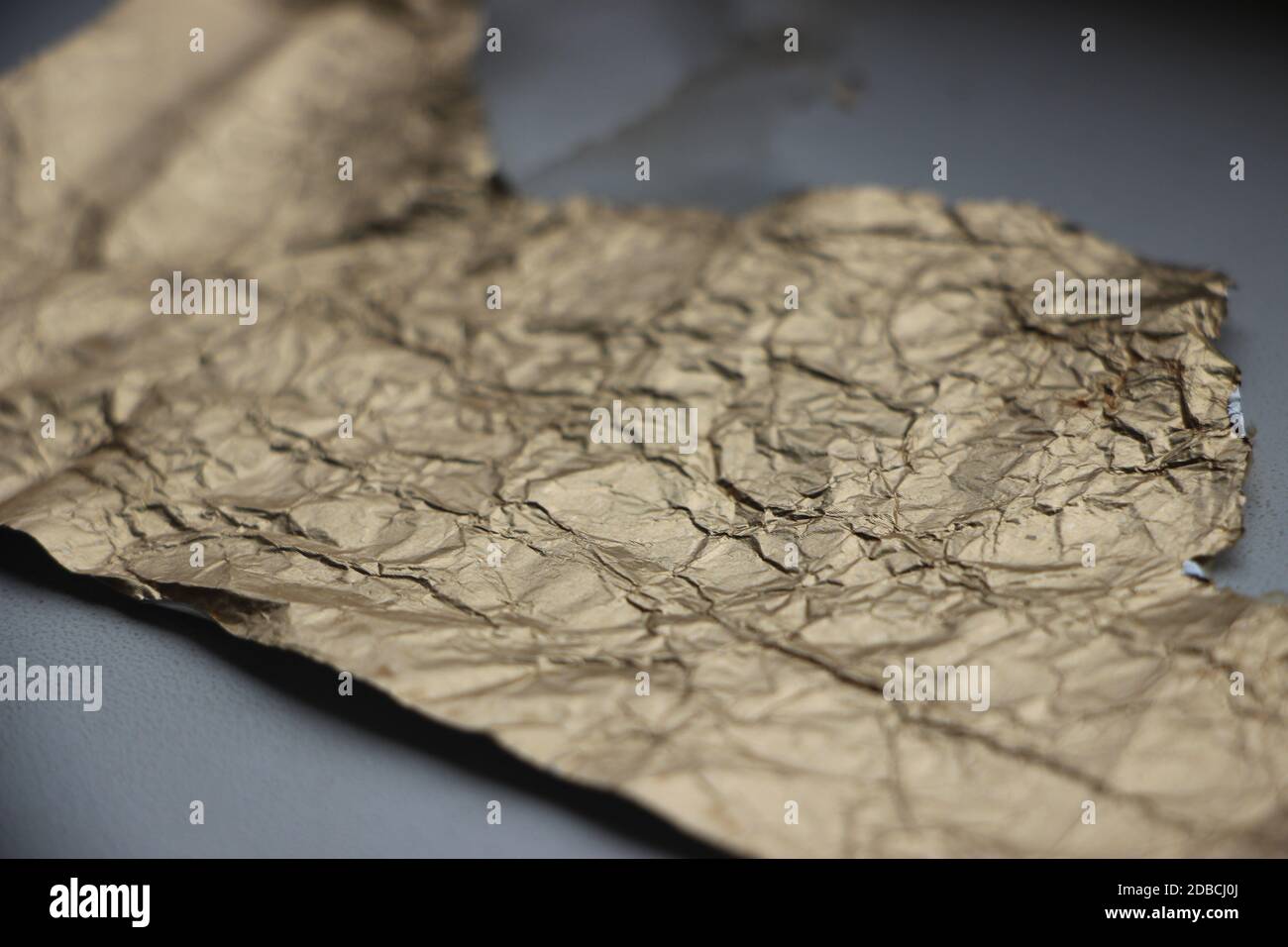 Crumpled and torn golden bronze shiny foil texture background Stock Photo