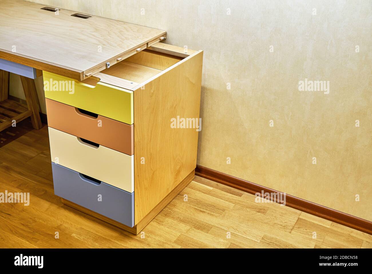 Plywood desk with multi color drawers during assembly. Fragment of the writing desk Stock Photo