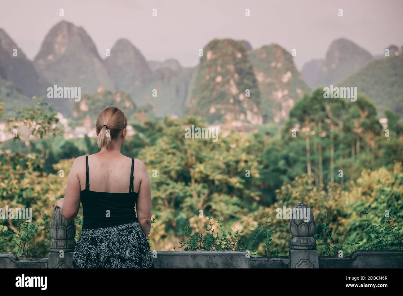 A beautiful mesmerizing picture of a female looking at the karts rocky foliage mountain scenery in Yangshuo, China Stock Photo