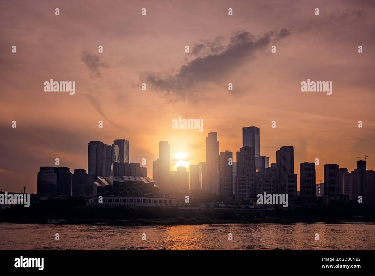 The silhouettes of buildings surrounded by the sea under the sunlight during the sunset in Chongqing, China Stock Photo