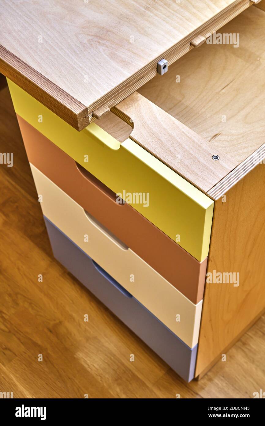 Plywood desk with multi color drawers during assembly. Fragment of the writing desk Stock Photo