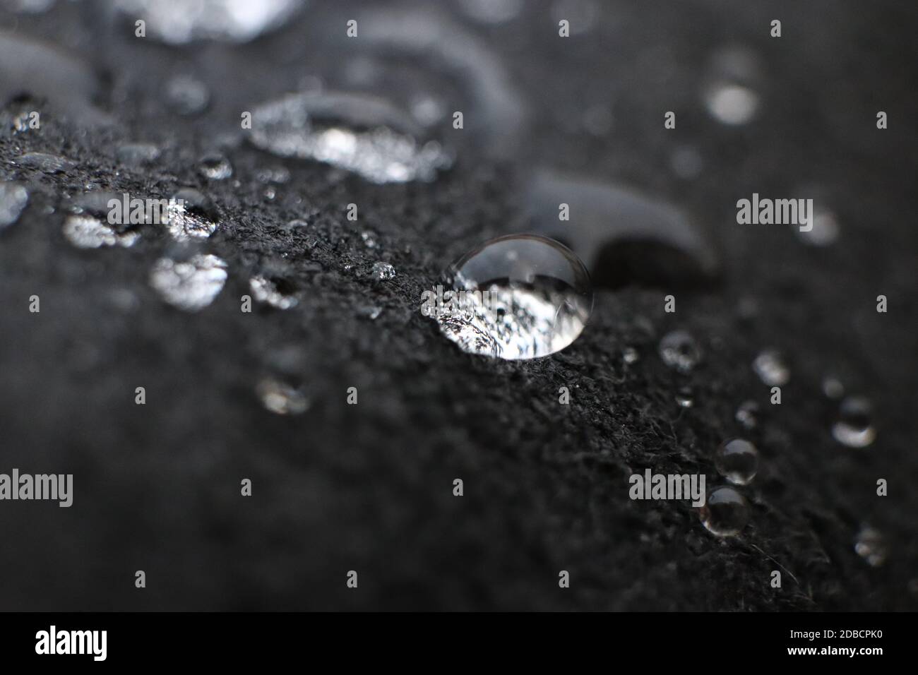 Water drops on black leather background texture. Macro Closeup. Stock Photo