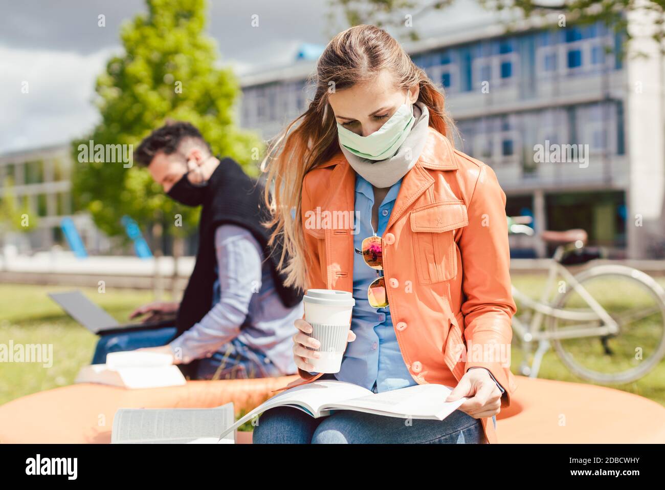 Man and woman practicing social distancing in university while learning and reading Stock Photo