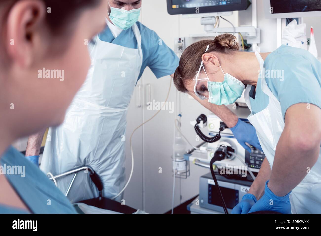 Doctor in surgery of hospital performing colonoscopy at sedated patient Stock Photo