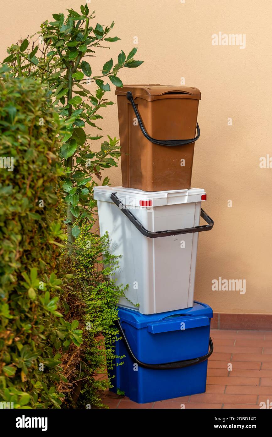 Bins of various colors for door-to-door recycling, stacked near a house Stock Photo