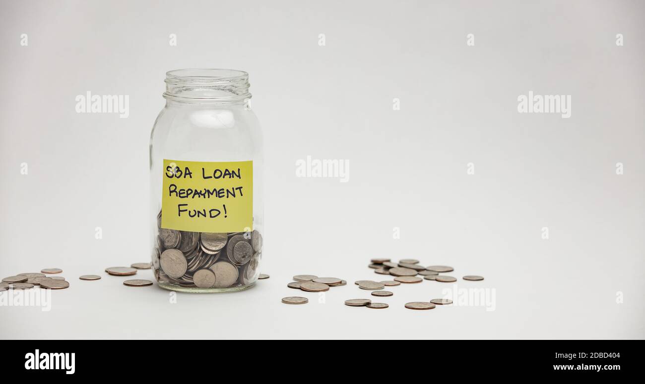 A glass jar holds many quarters, dimes and nickels for an SBA loan repayment. Stock Photo