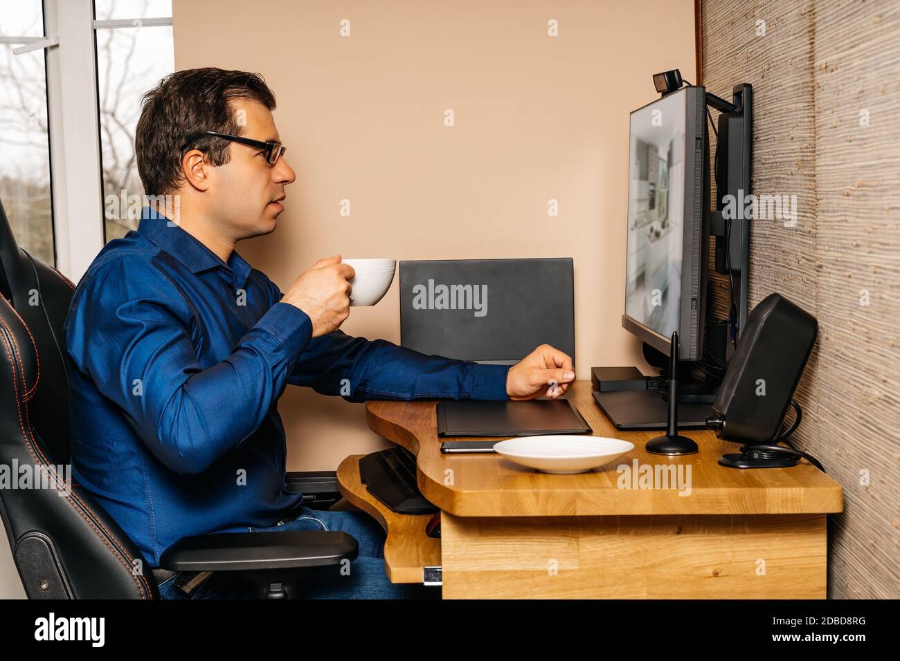 Businessman drinking coffee and working on computer from comfort of his home during covid 19 or