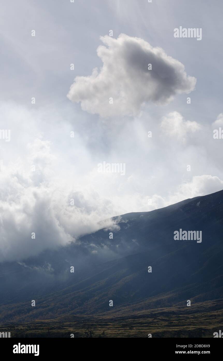 Clouds of volcanic smoke passing over Mount Etna slopes and hills in Sicily, Italy Stock Photo