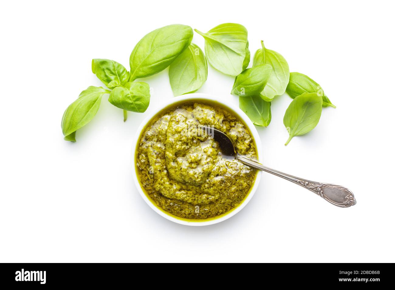 Green basil pesto dip sauce and basil leaves isolated on white